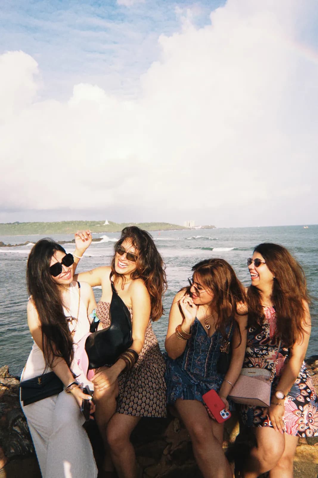 Friends laughing on the rocks by the sea